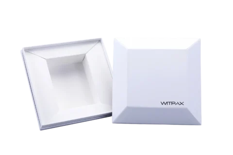 Two white, rectangular packaging boxes featuring beveled edges are positioned side by side. One box is closed, while the other is open, revealing a recessed interior.