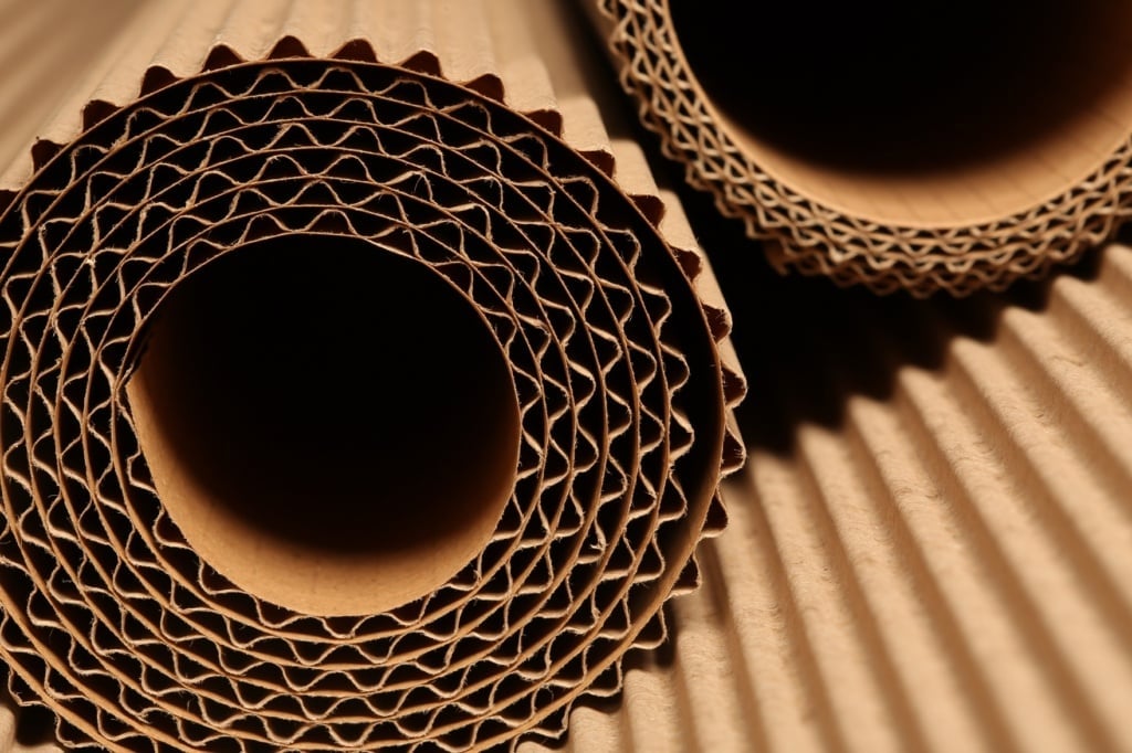 Close-up of rolled sustainable corrugated cardboard sheets highlighting their textured and layered structure. This visual invites the question: is using such materials for custom box packaging environmentally friendly?