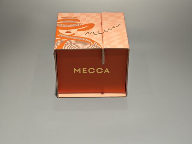 Orange Mecca box featuring a stylized face illustration