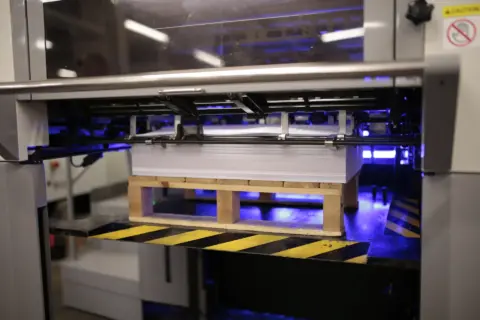 Printing press with stacked paper sheets ready for processing.