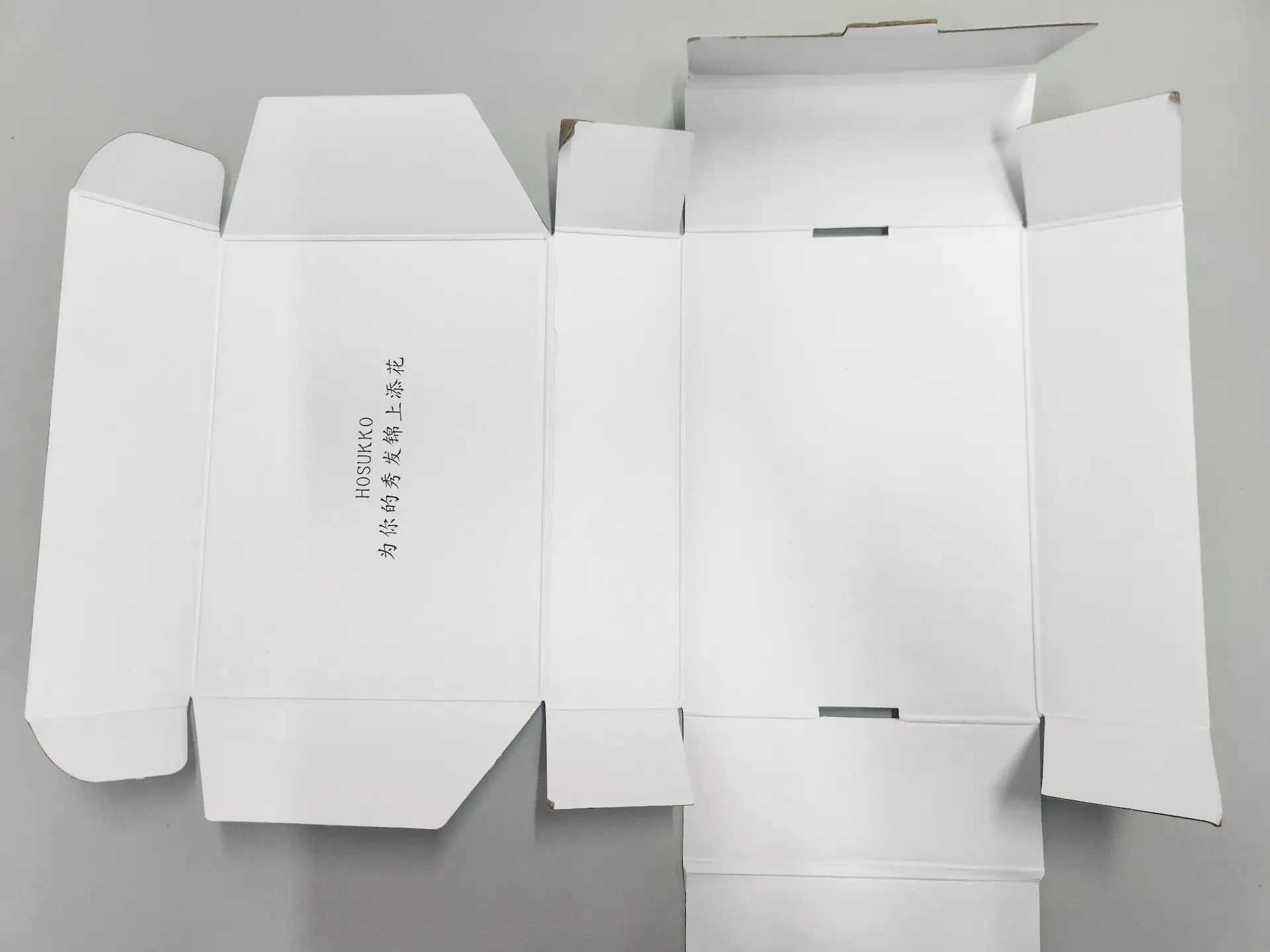 We are a manufacturer of custom box packaging. This image represents our product: an unfolded flat cardboard box with unique branding and design elements printed on the interior.